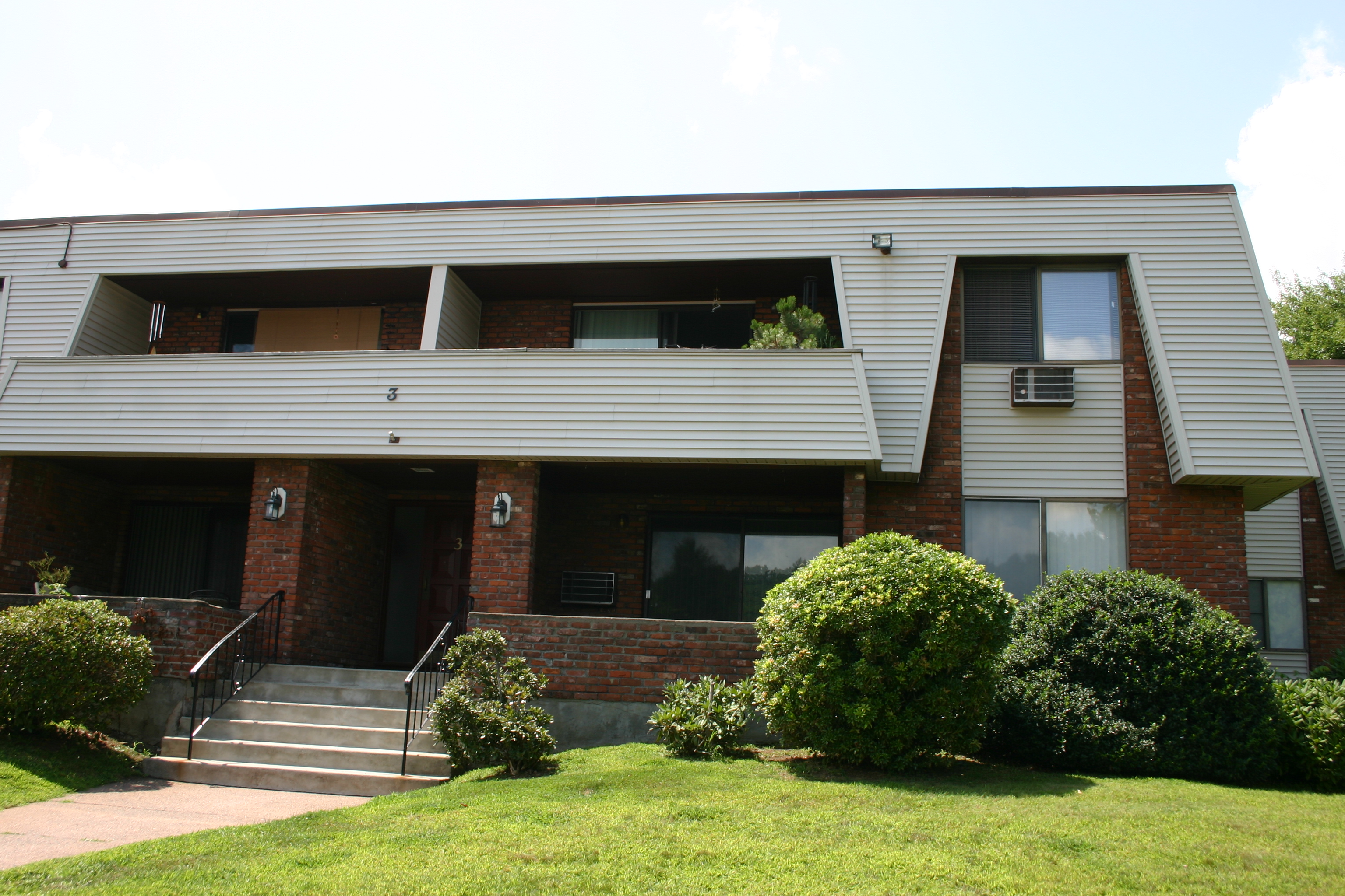 Two-story multi-family residential building with brick and beige siding facade